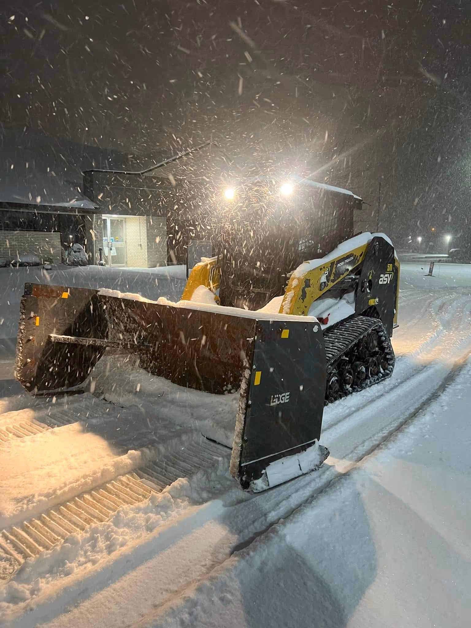 Lawn Impressions tracked snow plow clearing snow at night